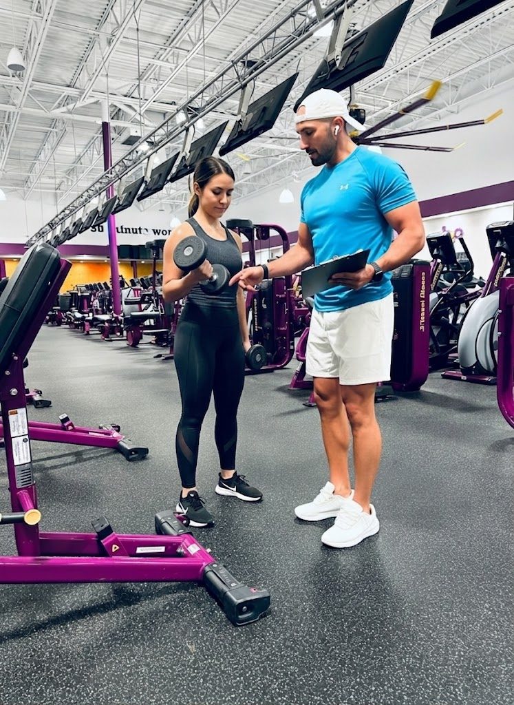 Gregory with a clipboard guiding a client through a dumbbell curl